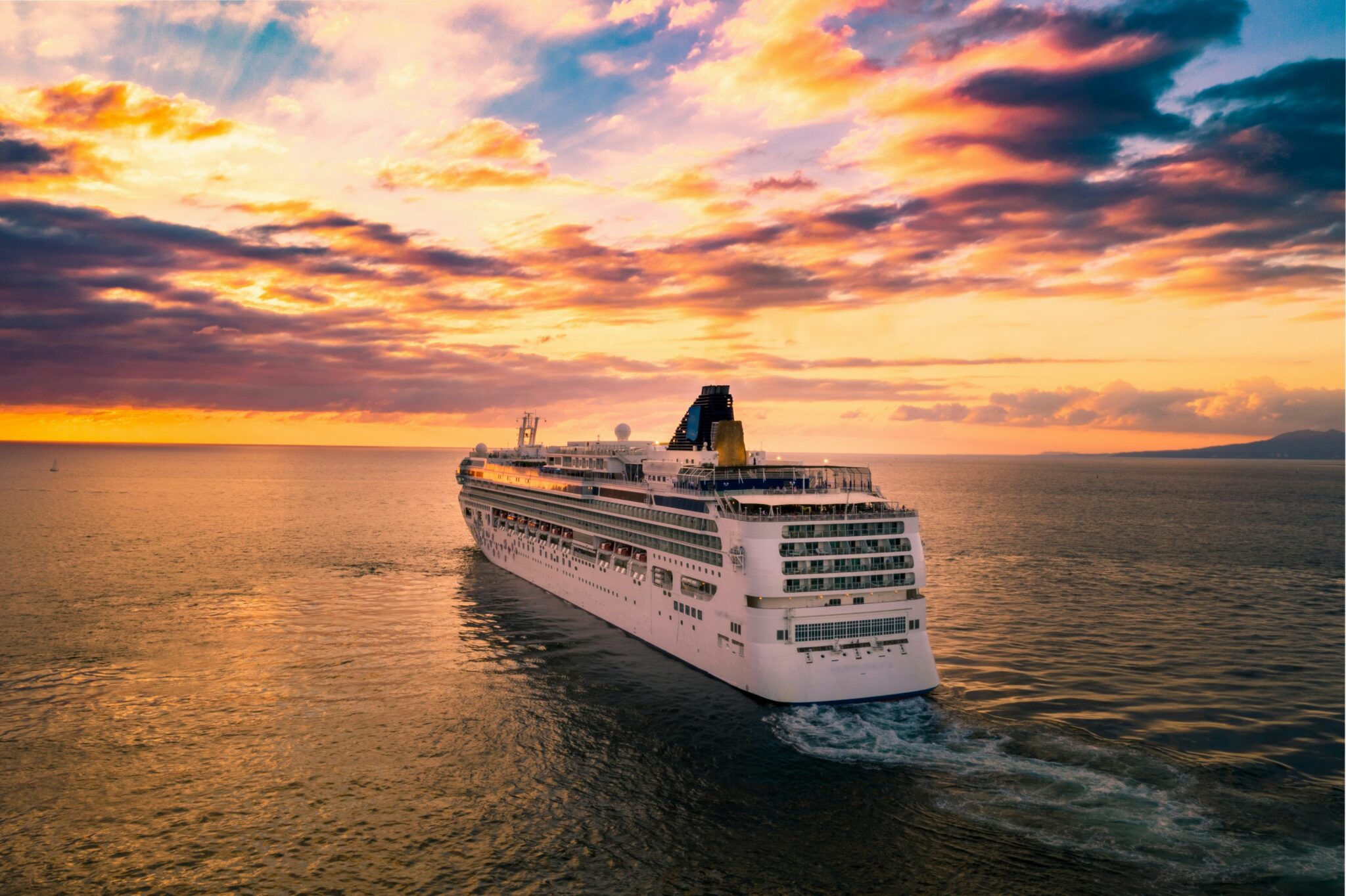 Large cruise ship sailing turquoise Caribbean water at sunset